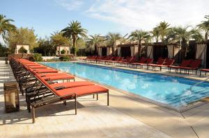 a large swimming pool with red chairs and palm trees at M Resort Spa & Casino in Las Vegas