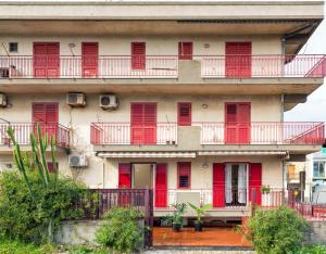 an apartment building with red doors and windows at Casa Susanna in Fondachello