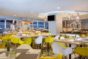 a dining room with tables and yellow chairs at KHAS Malioboro Hotel in Yogyakarta