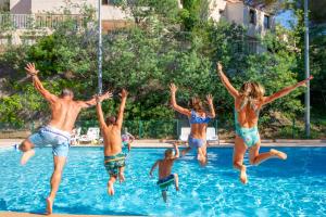 a group of people jumping into a swimming pool at Résidence Goélia Les Jardins d'Azur in Saint-Raphaël