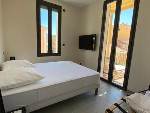 a white bedroom with a bed and a tv at Résidence Le Provence in Le Lavandou