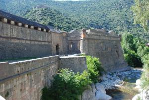 an old building with a wall next to a river at Appartement de charme au cœur d une cité médiévale in Villefranche-de-Conflent