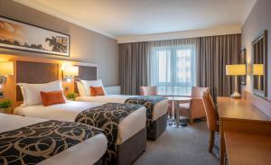 a hotel room with two beds and a desk at Clayton Hotel Dublin Airport in Cloghran