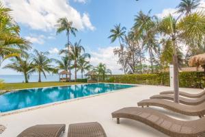 a swimming pool with chairs and the ocean in the background at Malee Beach A4 in Ko Lanta