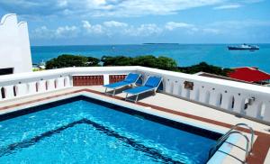 una piscina con due sedie blu e l'oceano di Maru Maru Hotel a Zanzibar City