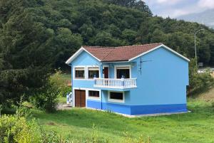 a blue house with a balcony on a hill at Casa Entremolin in Belmonte de Miranda