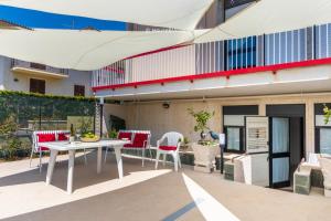 eine Terrasse mit einem weißen Tisch und Stühlen sowie ein Gebäude in der Unterkunft House&Villas - Eden Charming House in Avola
