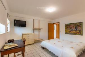 a bedroom with a bed and a desk and a tv at Eden Charming House in Avola +13 photos