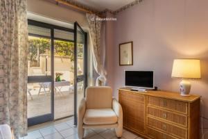 a living room with a tv and a chair and a window at Eden Charming House in Avola