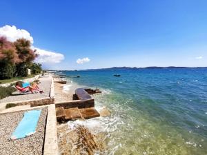 a group of people sitting on a beach next to the water at Sea Dream Apartments in Bibinje