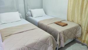 two beds in a room with a bag on top of them at Kana Hasya Homestay "Rumoh Jamee" in Meulaboh