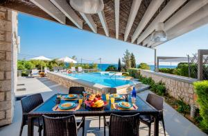 un patio con mesa y sillas y una piscina en Villa CostaMare - enjoy lazy days on the private Pool-Jacuzzi, en Pefki