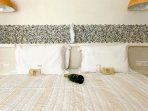 a bed with white pillows and a green bottle on it at Deluxe Studios & Suites Ageri-Milos in Adamantas