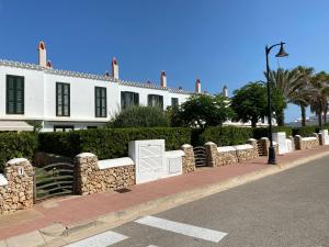 ein weißes Gebäude mit einer Steinmauer neben einer Straße in der Unterkunft ES BERRY 3 by SOM Menorca in Fornells