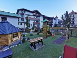 einen Spielplatz mit einer Holzbank und einem Gebäude in der Unterkunft Hotel Rauscher und Paracelsus in Bad Hofgastein