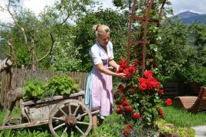 una donna in piedi in un giardino con fiori rossi di Falkenau a Chienes