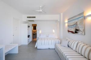 a white living room with a couch and a bed at Kalypso Hotel in Naousa