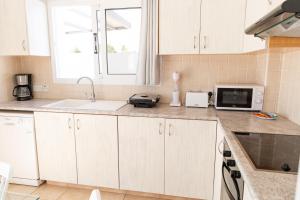 a kitchen with white cabinets and a microwave at Agia Thekla Villa Ekaterina 4 bdrm in Ayia Napa