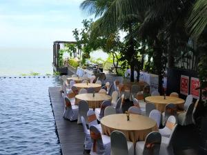 Golden Tulip Balikpapan Hotel & Suites في باليكبابان: صف من الطاولات والكراسي بجانب الماء