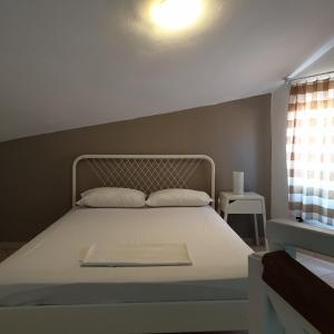 a bedroom with a bed with a white bed frame and a window at Amparoudes in Kriopigi