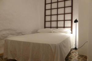 um quarto com uma cama com lençóis brancos e uma janela em Casa de los Joses em Alicante