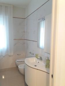 a white bathroom with a sink and a toilet at Casa Ely in Sottomarina