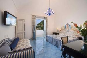 a bedroom with a bed and a couch and a table at Palazzo Marzoli charme Resort - Small Luxury Hotel in Positano
