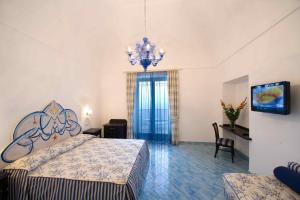 a bedroom with a large bed and a chandelier at Palazzo Marzoli charme Resort - Small Luxury Hotel in Positano