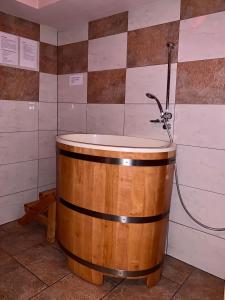 a wooden tub with a shower in a bathroom at Nocowanie Restauracja Wenecka in Kłobuck