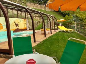 a garden with a swimming pool and green chairs at La Batllia in Sant Joan de les Abadesses