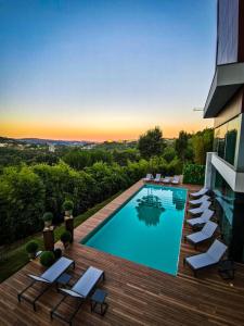 a swimming pool on a deck with chairs next to a building at Penafiel Park Hotel & Spa in Penafiel