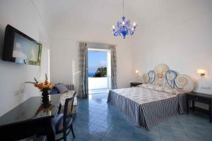 a bedroom with a bed and a table and a chandelier at Palazzo Marzoli charme Resort - Small Luxury Hotel in Positano