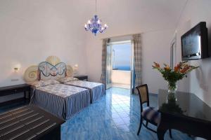 a bedroom with a bed and a table and a television at Palazzo Marzoli charme Resort - Small Luxury Hotel in Positano