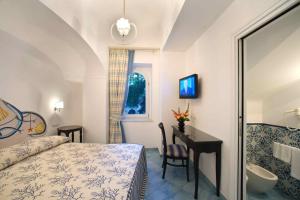 a bedroom with a bed and a desk and a sink at Palazzo Marzoli charme Resort - Small Luxury Hotel in Positano