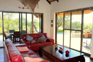 a living room with a red couch and a table at Bushvilla Umoja Kruger in Phalaborwa