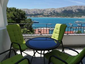 two chairs and a table on a balcony with a view of the water at Apartments Andrea in Baška