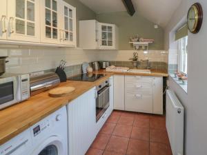 a kitchen with white cabinets and a washer and dryer at Meadow View in Banbury