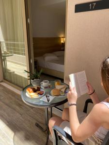 een vrouw aan een tafel die een boek leest bij Marvel Deluxe Rooms in Heraklion