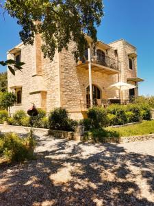 un gran edificio de piedra con un árbol delante de él en Villa Ermis - The Cretan Castello, en Kástellos