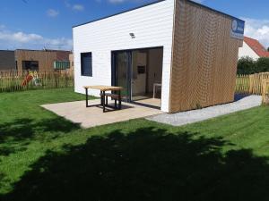 a small white building with a picnic table in a yard at ETABLISSEMENT CHEZ JULES in Ambleteuse