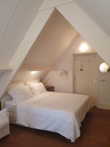 a bedroom with a white bed in a attic at Chapeau ! in Garderen