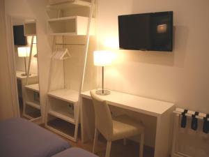 リスボンにあるリスボン スタイルのデスク、壁掛けテレビが備わる小さな客室です。