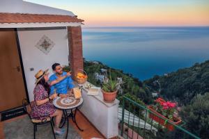 a man and woman sitting at a table on a balcony with the ocean at Villa Mare in Amalfi