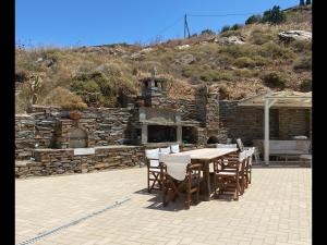 a patio with a table and chairs and a stone fireplace at Villa au paradis bleu in Melissaki