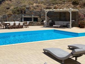 a pool with two chairs and a table and a patio at Villa au paradis bleu in Melissaki