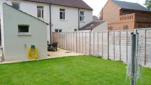 einen Hinterhof mit einem Zaun und einem gelben Schlauch in der Unterkunft Bassett House with 3 bedrooms, fast Wi-Fi and off road parking in Kent