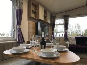 a wooden table with glasses and a bottle of wine at Lakes Breaks - 6 Meadows in Tattershall