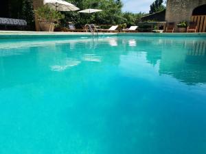 una gran piscina azul con sillas y sombrilla en Mas provençal à proximité du Pont Du Gard, en Sernhac