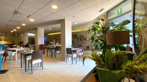 une salle à manger avec des tables, des chaises et des plantes dans l'établissement Hotel Europa, à Ancône