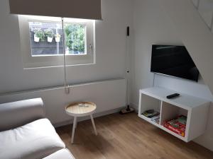 salon z kanapą, telewizorem i stołem w obiekcie Picco Bello w Zandvoort